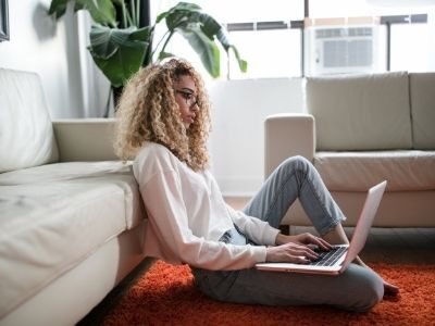 Lady remote working on a laptop on her living room floor